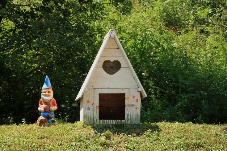 Little dwarf sits next to dog house